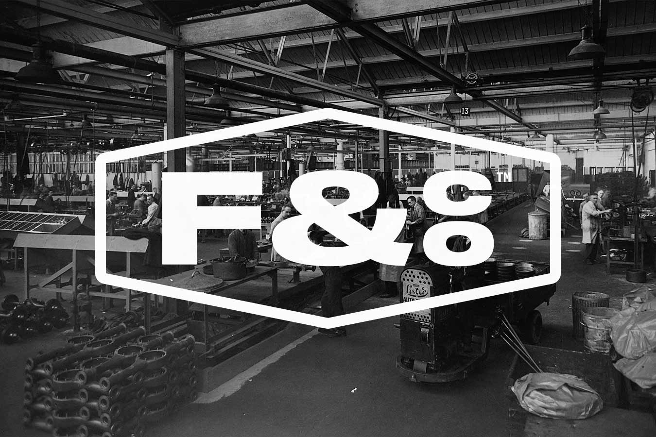 A factory warehouse with workers inside and a stamped F&co logo covering the front, depicted in black and white.