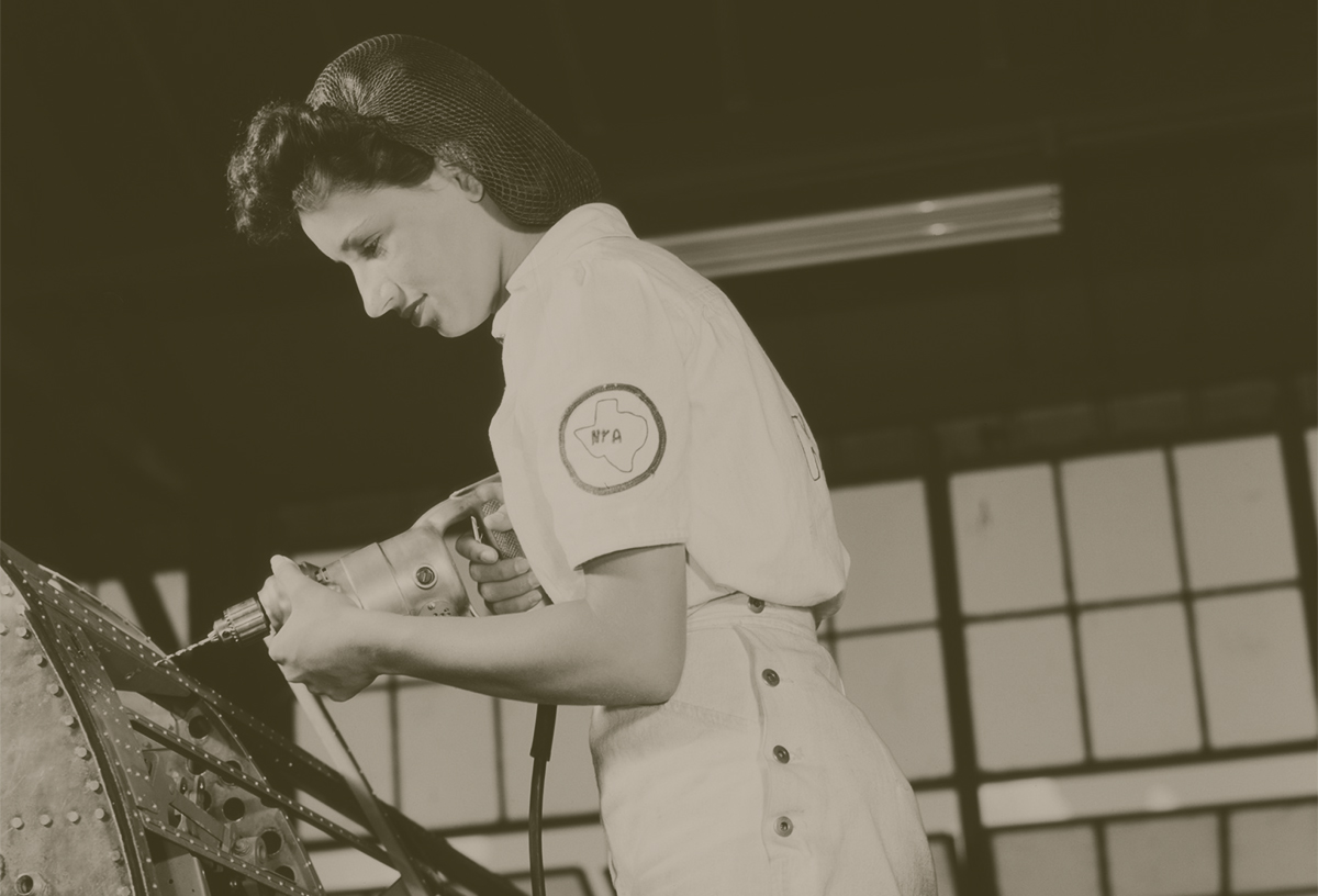 A black and white image of a woman drilling metal machinery.