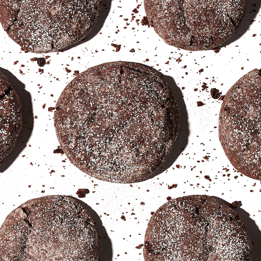 Seven chocolate cookies sprinkled with powdered sugar, arranged in a circle.