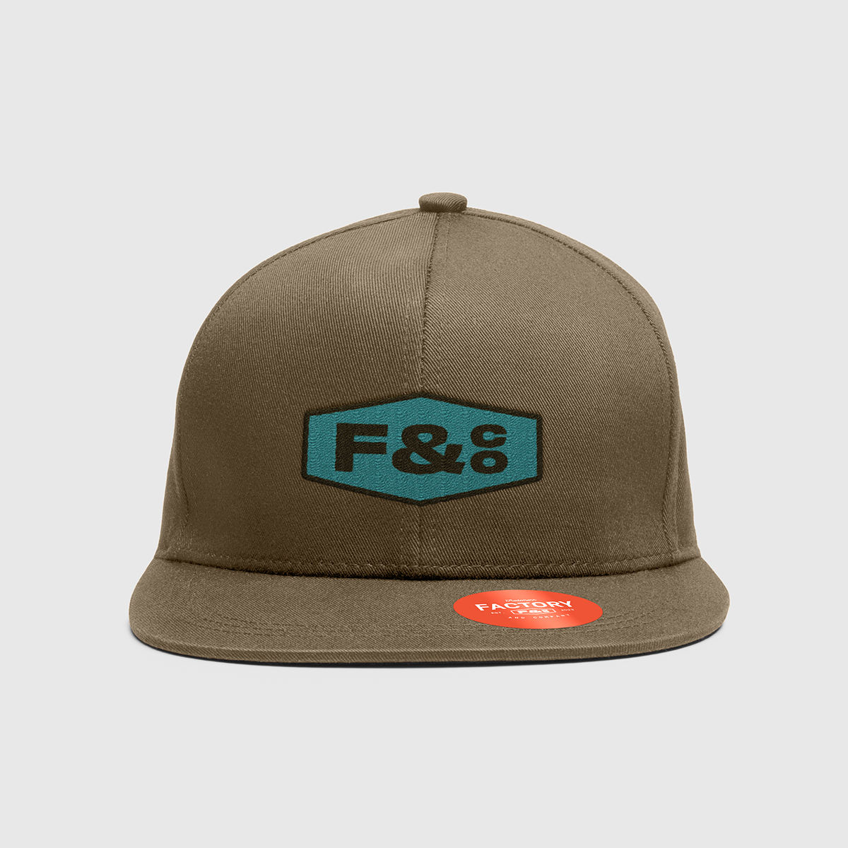 A light-brown flat-brim baseball cap with a 'F&co' patch on the front and 'Factory' sticker on the brim. 